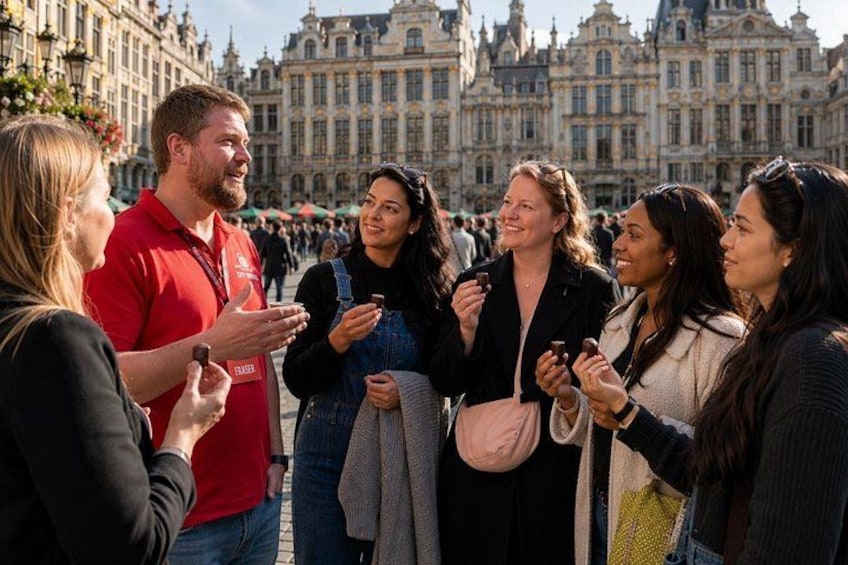 A group of people standing in a public square with historic buildings in the background. 1