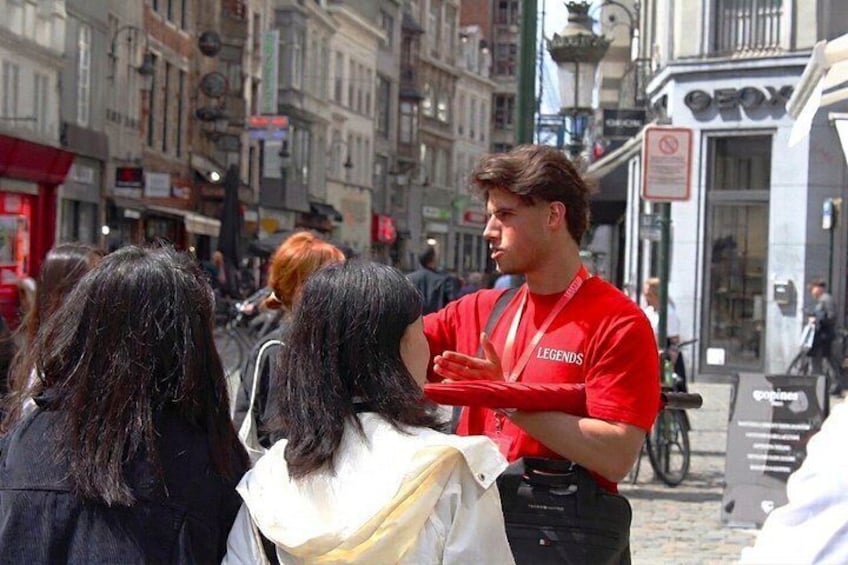 Escena callejera con una persona de camisa roja de pie hablando con dos mujeres. 5