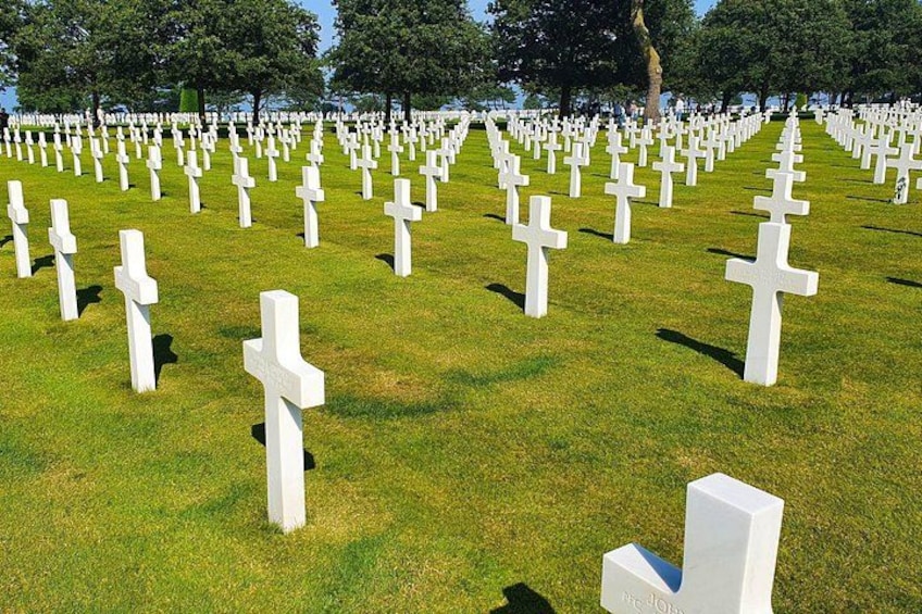 Ein Friedhof mit zahlreichen weißen Kreuzen, die in Reihen angeordnet sind. 1