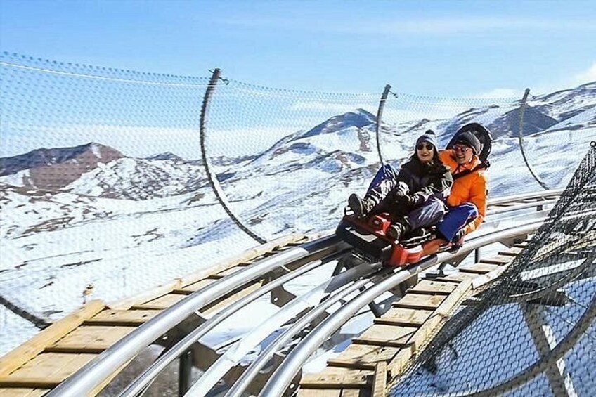 Un paysage montagneux enneigé avec une piste de montagnes russes en bois et des garde-corps métalliques. 5