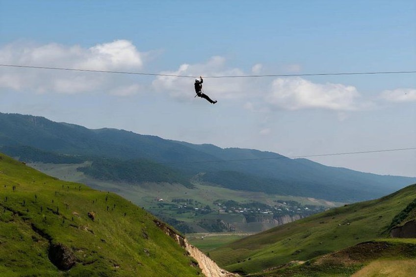 Une personne pratiquant le saut à l’élastique au-dessus d’une vallée, avec des collines verdoyantes et un ciel dégagé. 2