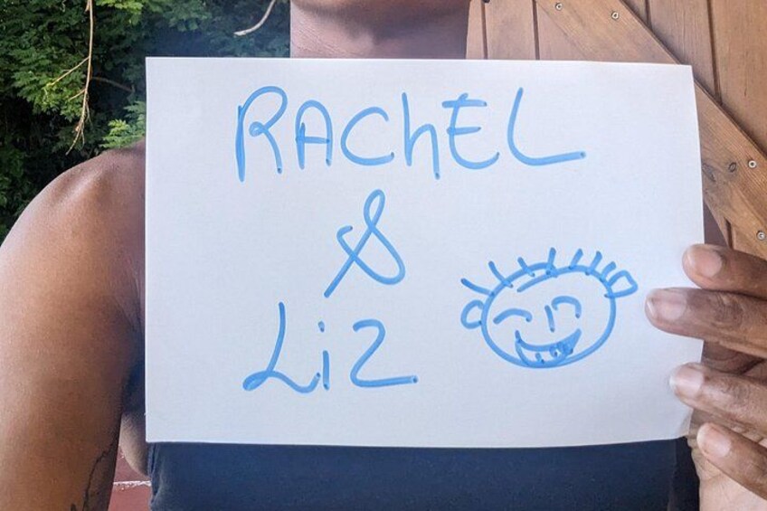 Una persona sostiene un cartel con el nombre 'Rachel' y un dibujo de una cara sonriente. 5