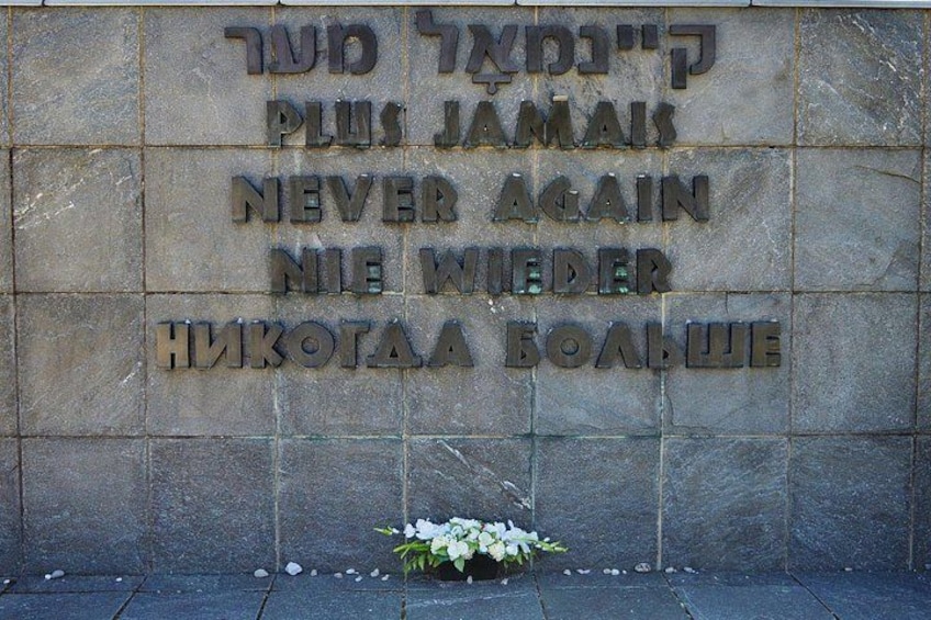 Eine Steinsäule mit eingraviertem Text und einem kleinen Strauß weißer Blumen. 3