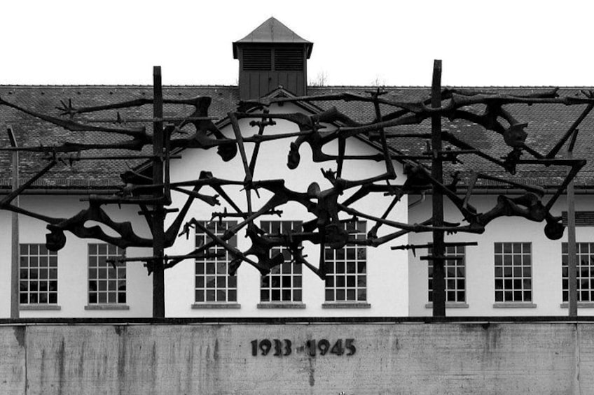Ein Gebäude mit der Jahreszahl '1913-1945' an der Fassade, umgeben von einer aufwendigen Metallskulptur. 2