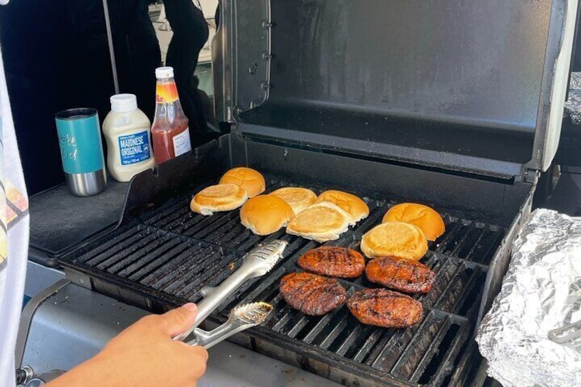 A grill with hamburgers and buns being cooked. 4
