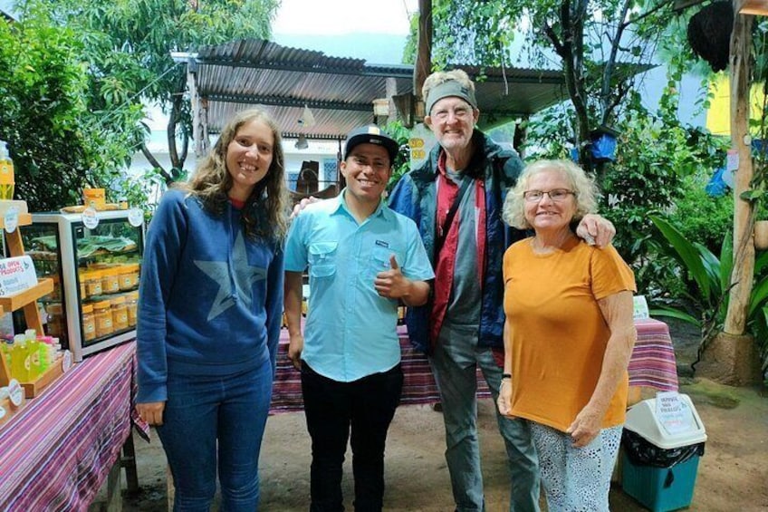 A group of people standing outdoors with a market stall in the background. 1
