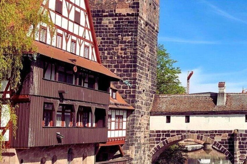 Ein traditionelles Fachwerkhäuschen, ein Steinbrunnen und eine Steinbrücke über dem Wasser. 1