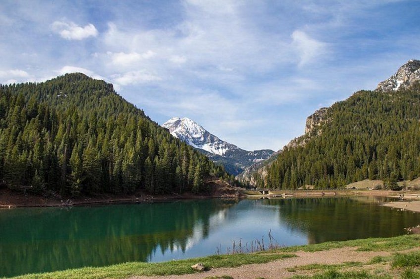 Ein See, umgeben von bewaldeten Bergen unter blauem Himmel. 2