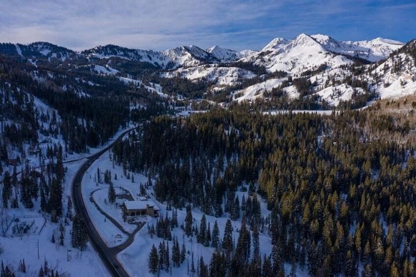 Ein verschneites Gebirge mit einer kurvenreichen Straße, die durch einen Wald führt. 3