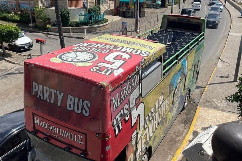 Un autobus festivo rosso con la scritta 'MARGARITAVILLE' e 'JAMAICA' sul retro, parcheggiato in strada. 2