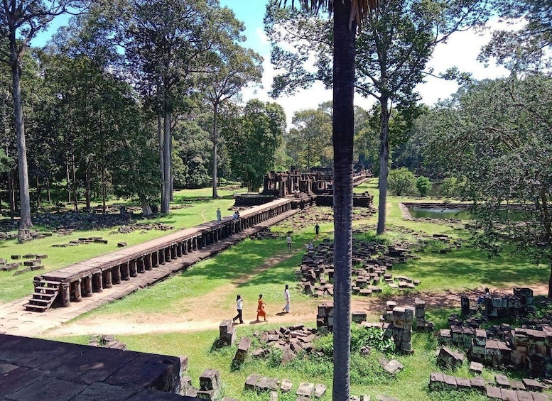 An ancient stone bridge in a lush, green park with scattered ruins and trees. 1