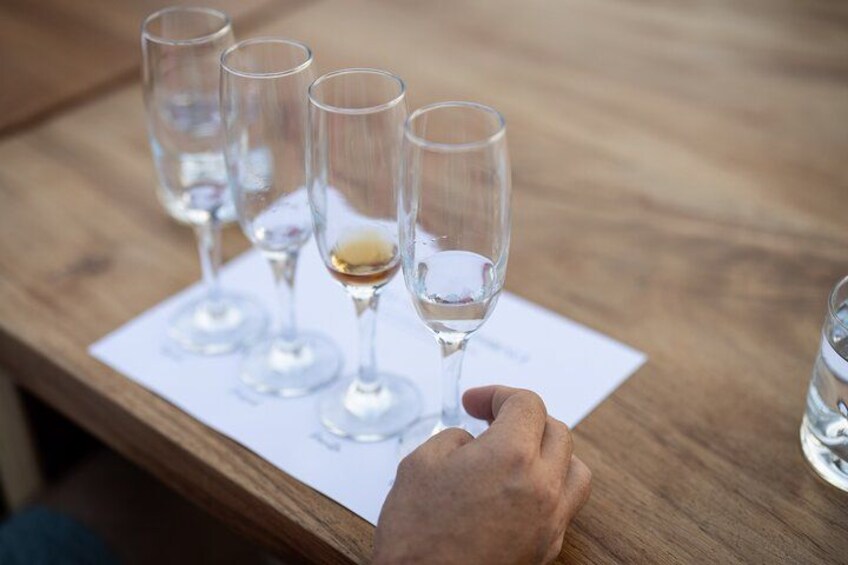 Una mesa de madera con cuatro copas de vino y una mano sosteniendo una. 2