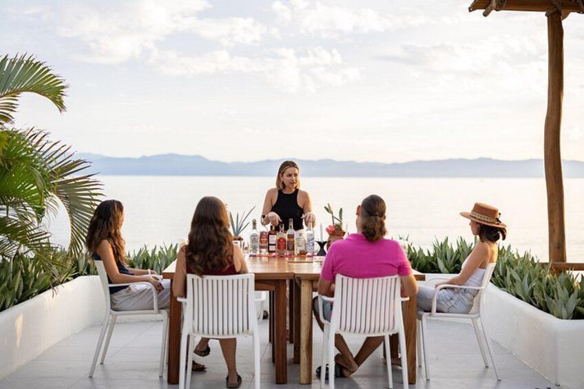 Un groupe de personnes est assis à une table à l’extérieur, avec une vue sur une étendue d’eau et des montagnes au loin. 5