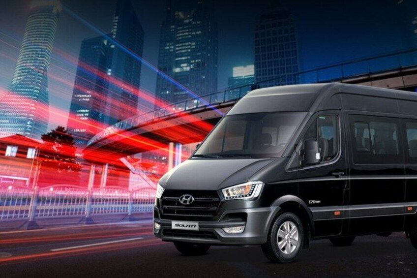 A black Hyundai Solati van parked on a city street at night with a cityscape in the background. 2