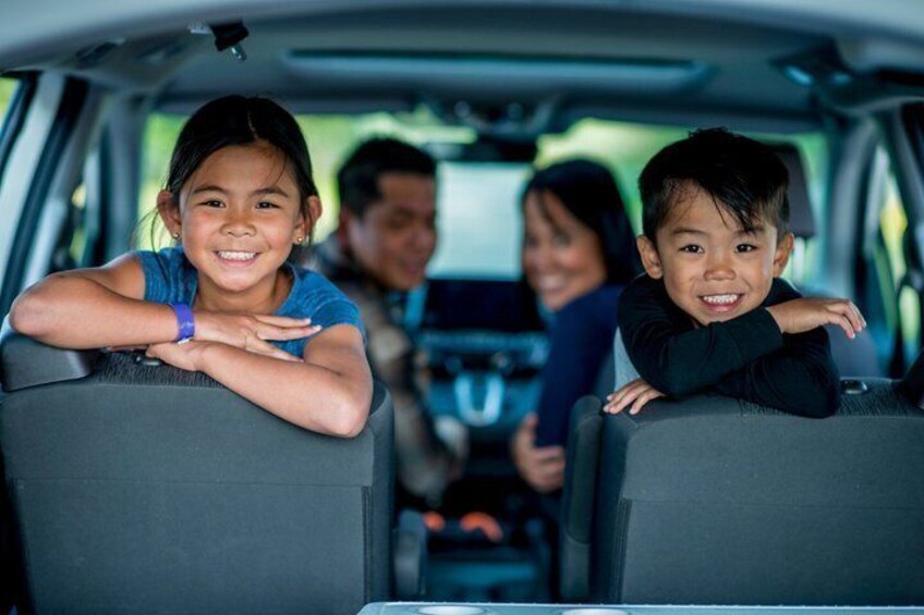 Interno auto con due bambini appoggiati ai sedili posteriori e un adulto alla guida. 5