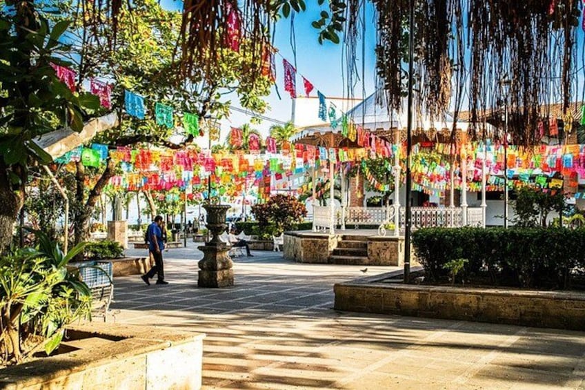 A plaza with colorful flags, a fountain, and a person walking. 2