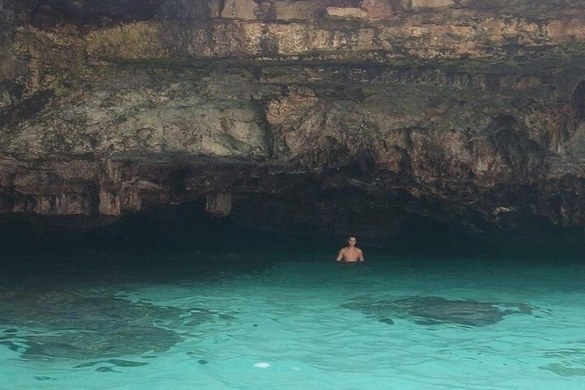 Una persona che nuota in una piscina cristallina blu, con scogliere rocciose sullo sfondo. 3