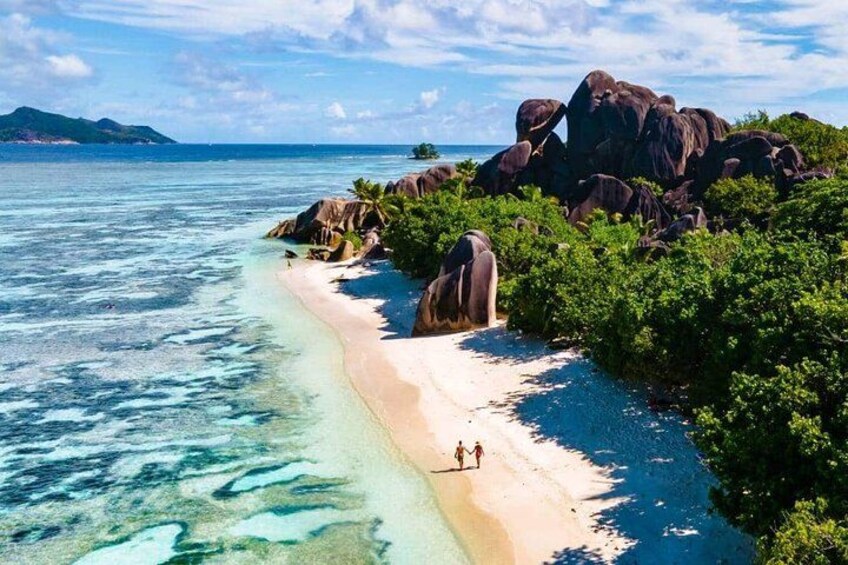 A beach with clear turquoise water, a sandy shore, and large rock formations. 2