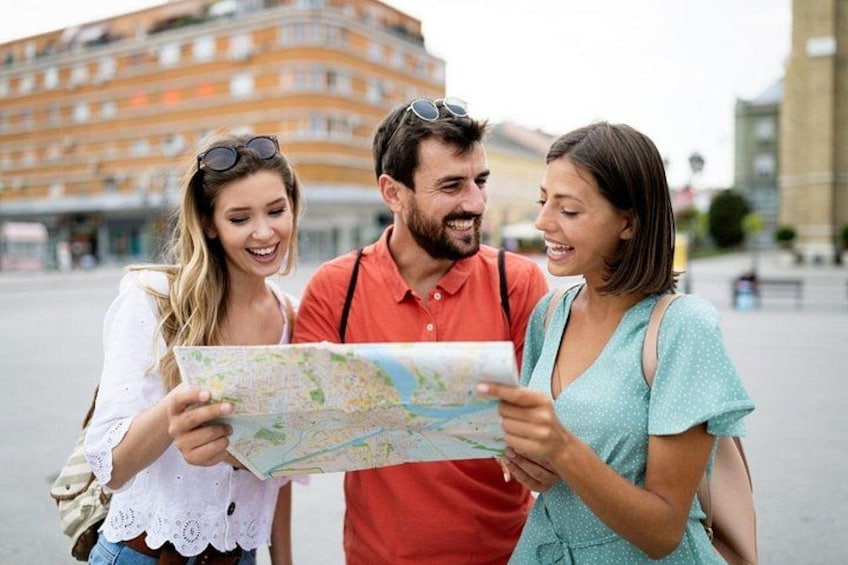 Three people examining a map outdoors with buildings in the background. 2