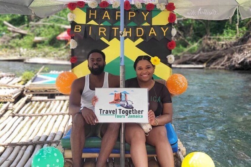 A couple on a boat with a 'Happy Birthday' sign and a 'Travel Together Tours Jamaica' sign. 5