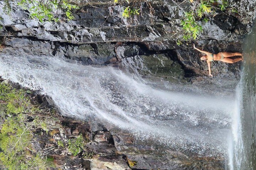 A waterfall cascading over a rocky cliff with a person standing on the edge. 4