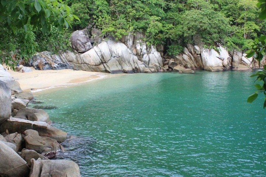 Une plage aux eaux turquoise, bordée de rochers blancs et d’une végétation luxuriante. 4