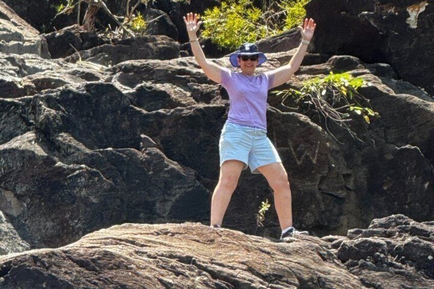 A person standing on a rock with arms raised. 4