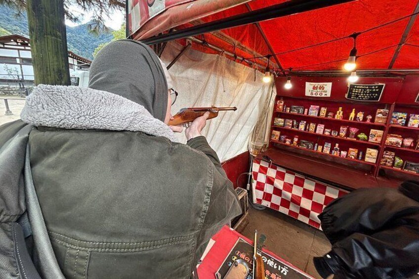 Una persona usando un teléfono inteligente en un puesto de comida rojo con estantes llenos de aperitivos. 5