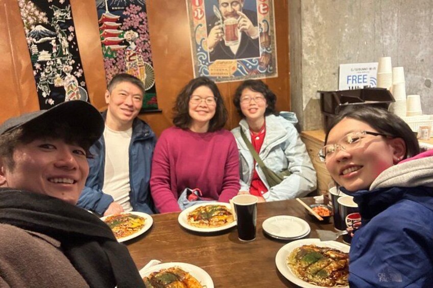 Un gruppo di persone sedute a un tavolo con piatti di cibo e bevande. 5