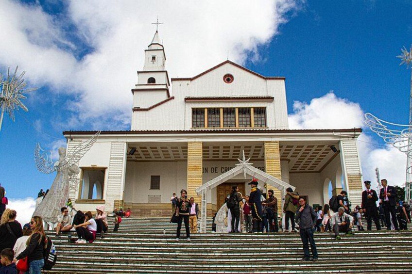 Una iglesia blanca con un campanario, escalones que conducen a la entrada y un cielo azul despejado. 1