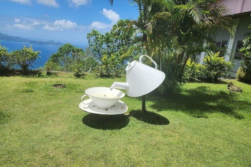 Un ensemble de mobilier de jardin blanc, placé sur une pelouse verdoyante, avec vue sur l’océan et une maison en arrière-plan. 1