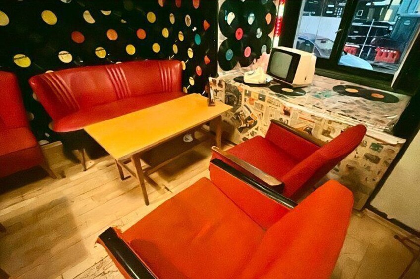 Ein stilvolles Zimmer im Retro-Design mit einem roten Sofa, einem gelben Tisch und einem Fernseher auf einem Tisch. 3