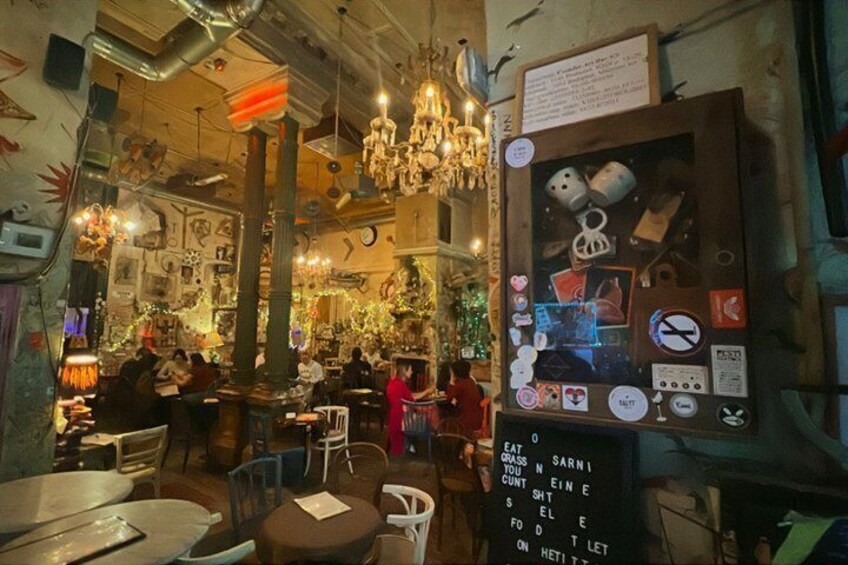 Ein gemütliches Restaurantambiente mit hängenden Lampen, einer Kreidetafel als Speisekarte und verschiedenen Wanddekorationen. 2