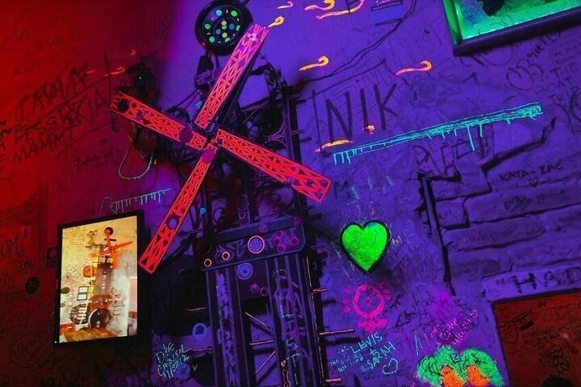 Eine mit Graffiti beschmückte Wand mit Neonlichtern, einem roten X und einem grünen Herz. 4