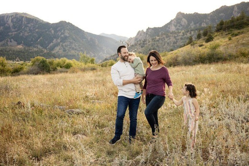 A family of four in a grassy field with mountains in the background. 4