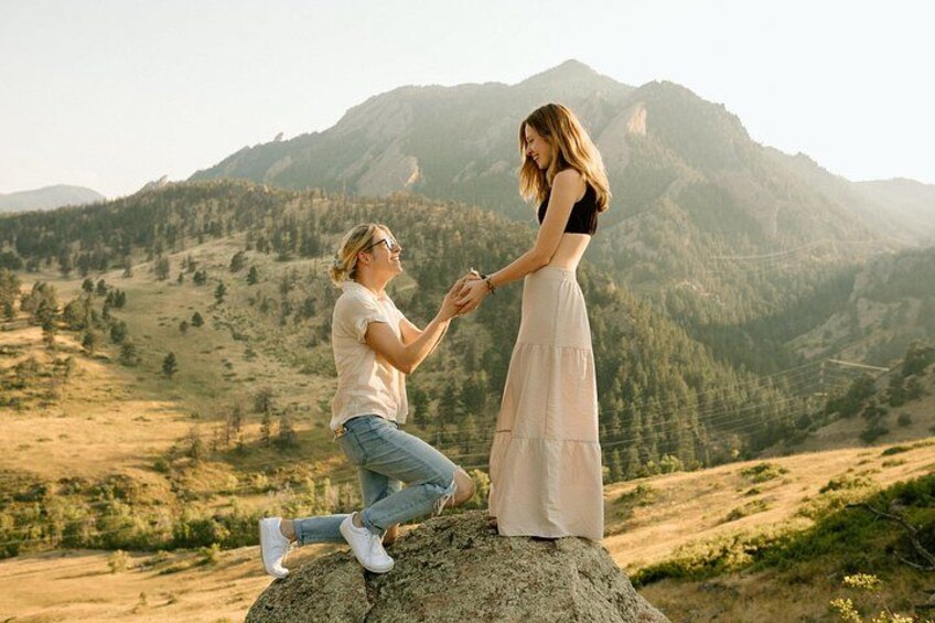 A person kneeling on a rock with a mountain landscape in the background. 3