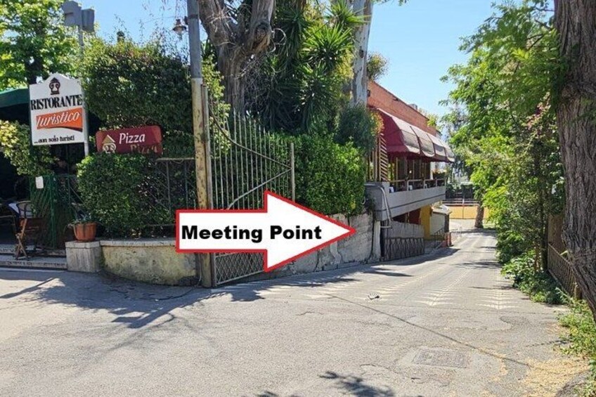 Una calle con una pizzería y un cartel que indica un punto de encuentro. 2