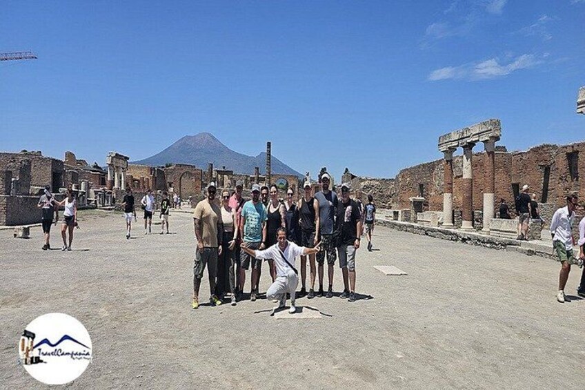 Un grupo de personas de pie en unas ruinas antiguas con un volcán al fondo. 4