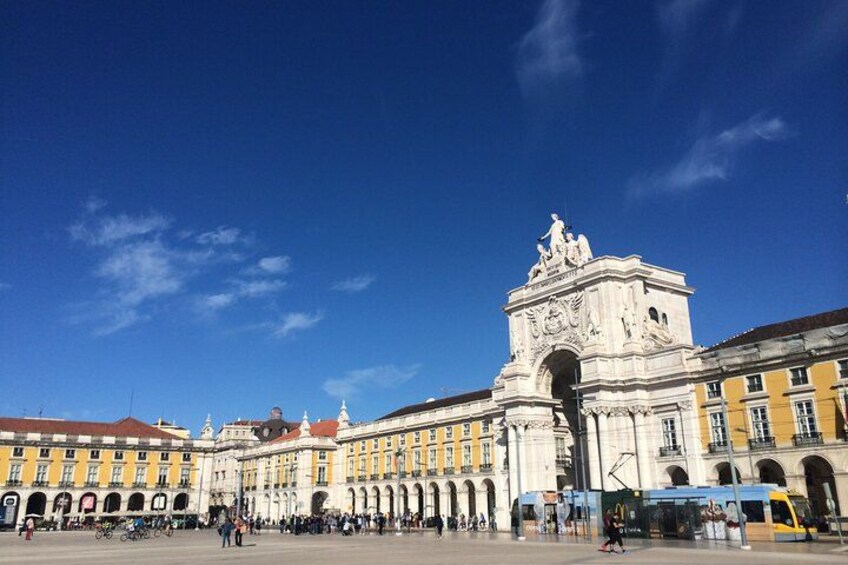Una piazza storica con un arco imponente, un tram e architettura classica. 2