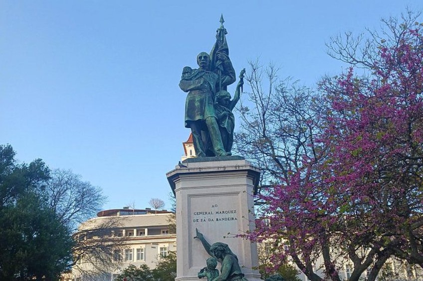 Una statua di una figura storica su un piedistallo, con un edificio sullo sfondo. 5