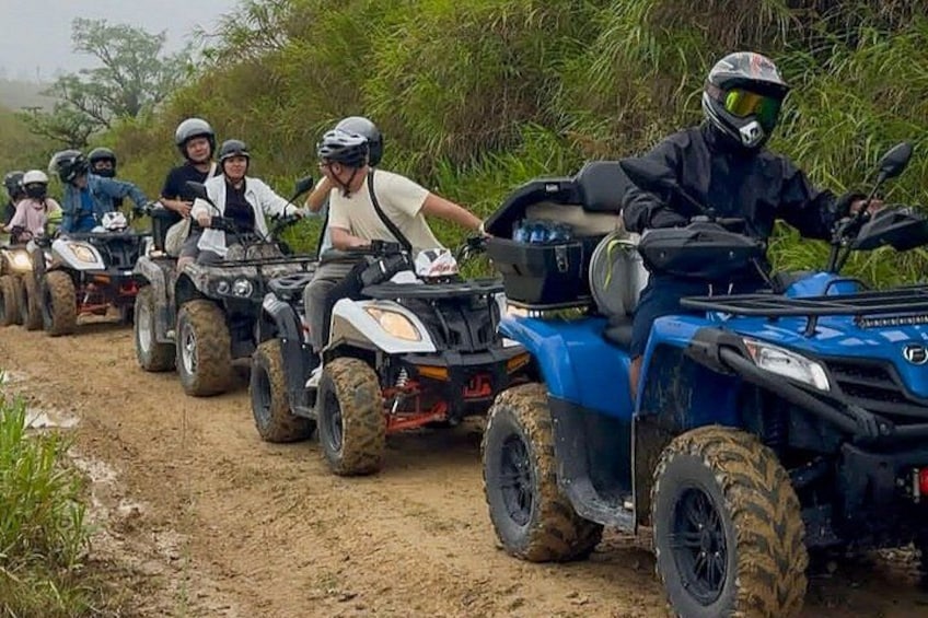 A group of people riding ATVs on a dirt path surrounded by vegetation. 5