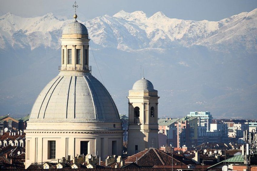Un grande edificio a cupola con una struttura più piccola adiacente, sullo sfondo di montagne innevate. 3