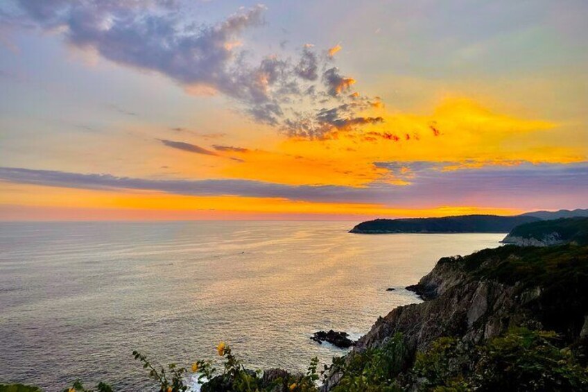 Ein Küsten-Sonnenuntergang bei klarem Himmel, ruhiger See und steinigen Klippen. 2