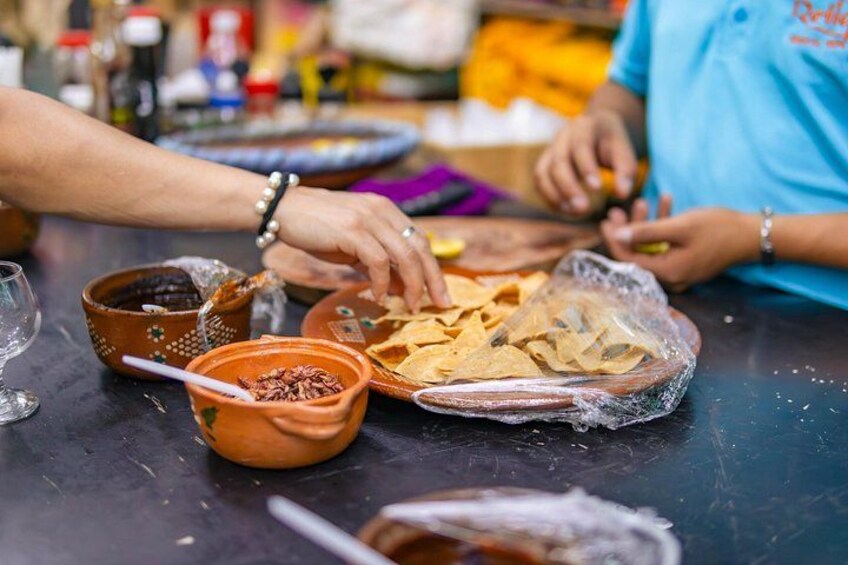 Eine Person bereitet Essen zu, mit einer Schüssel Soße und Tortilla-Chips auf dem Tisch. 5