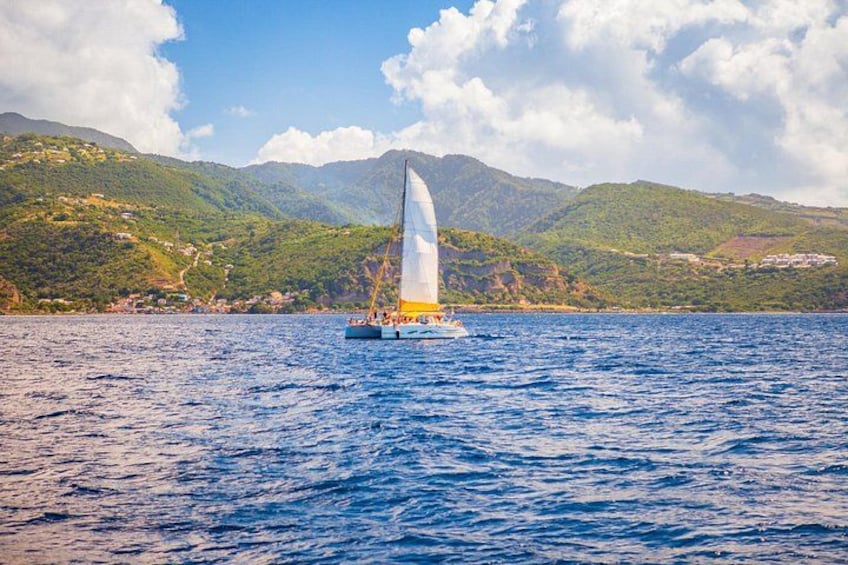 A sailboat on a calm sea with a mountainous landscape in the background. 1