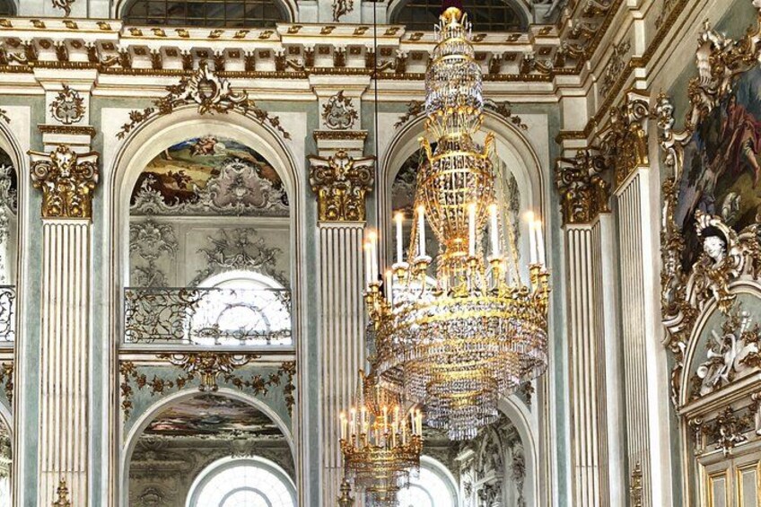 An ornate chandelier, intricate ceiling frescoes, and classical architecture. 2