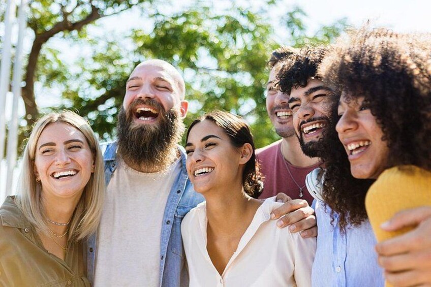 A group of people outdoors, possibly in a park or public space, with trees and a clear sky in the background. 2