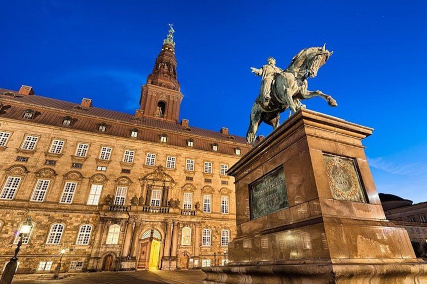 A historic building with a clock tower and a statue of a figure on horseback. 5