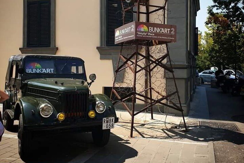 A vintage car parked in front of a building with a sign that reads 'BUNKART.' 5