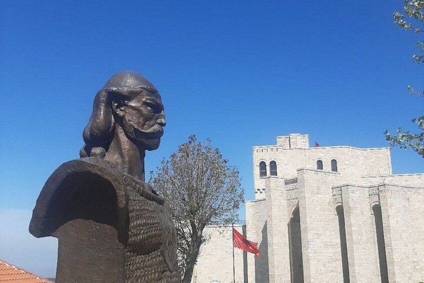 A statue in front of a historic building with a flag. 2